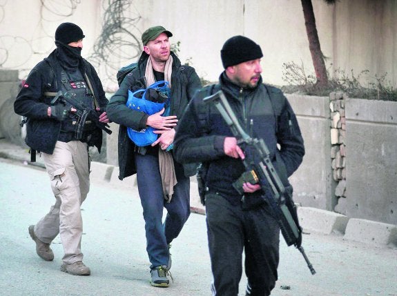 Dos agentes escoltan a un español junto a la embajada de Kabul después del asalto que se saldó con dos agentes muertos. 