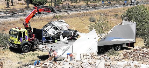 Operarios retirando, con ayuda de una grúa, los restos del camión accidentado en la autovía A-7 en la madrugada de ayer, cuyo conductor resultó herido leve.