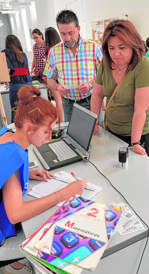 Un padre y una madre, ayer mañana, entregando en depósito los libros de sus hijos al banco de intercambio. 