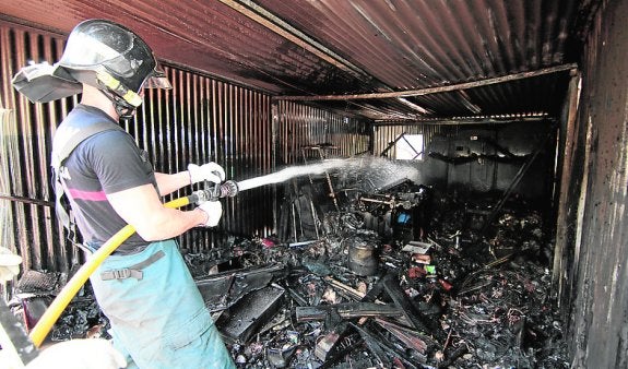 Un bombero apaga el fuego en el garaje calcinado.