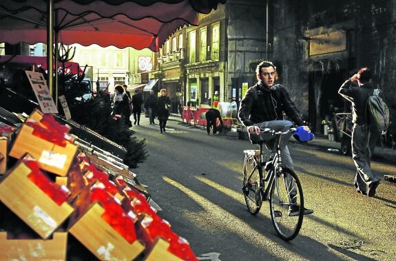 Un joven pasea en bicicleta por el mercado de Borough ante un puesto de frutas locales. 