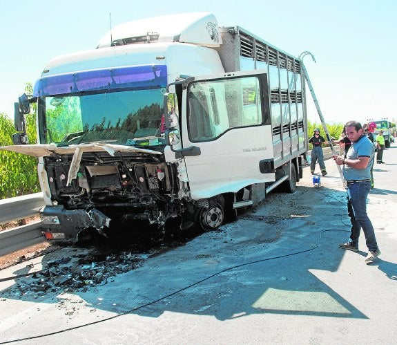 Bomberos trabajan en la retirada del camión contra el que chocó el conductor fallecido. 