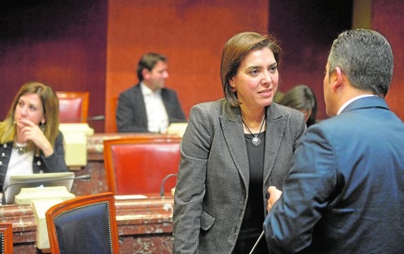 La consejera Encarna Guillén habla con un diputado durante una sesión en la Asamblea. 