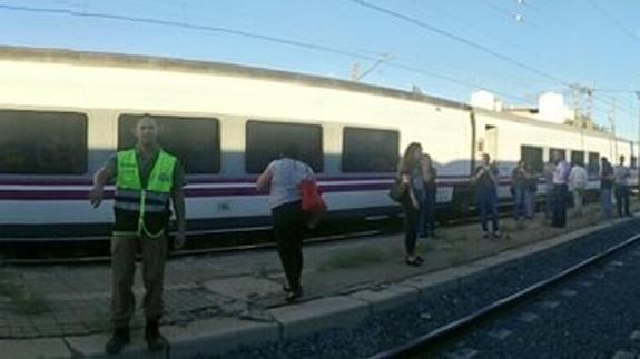 Algunos pasajeros esperan en el anden de La Roda con la locomotora averiada.