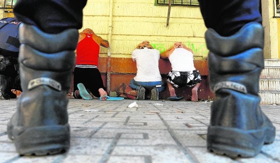 Varios detenidos en la redada de La Paz de 2015, vigilados por un policía. :: fran manzanera/agm
