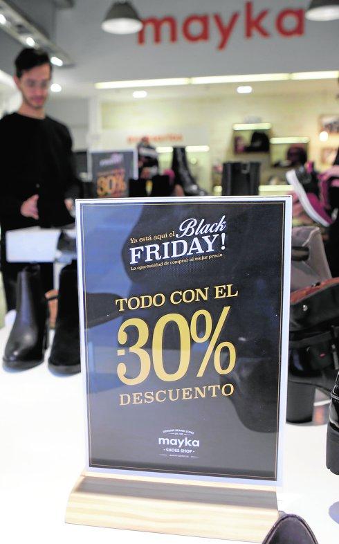 Un dependiente coloca género en una de las primeras tiendas del centro comercial Thader en aprovechar el 'black friday'.