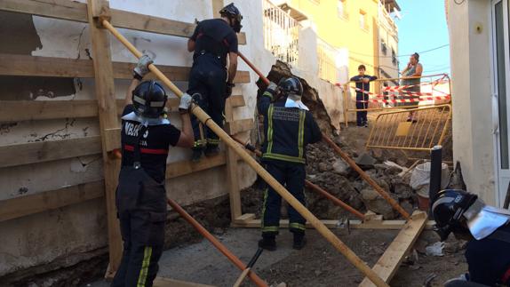 Efectivos de bomberos apuntalan la vivienda. 