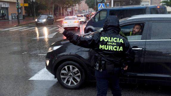 Un agente indica el paso a un vehículo, este sábado en Murcia. 