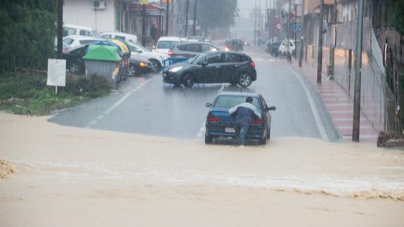 Un conductor tiene que empujar su coche después que se le parara al cruzar una rambla en Torreagüera.