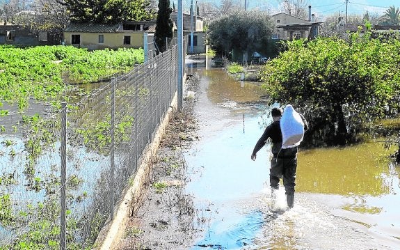 José pasa por el agua cargado con pienso para sus animales.
