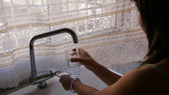 Una mujer se llena el vaso de agua. 
