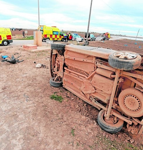 El vehículo, volcado en el bancal. Al fondo, dos ambulancias.