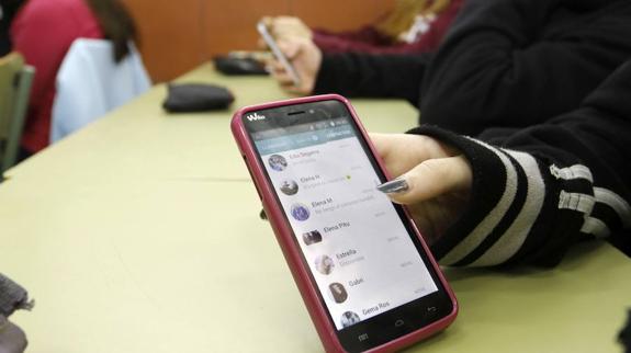 Una joven sostiene su móvil en clase. 