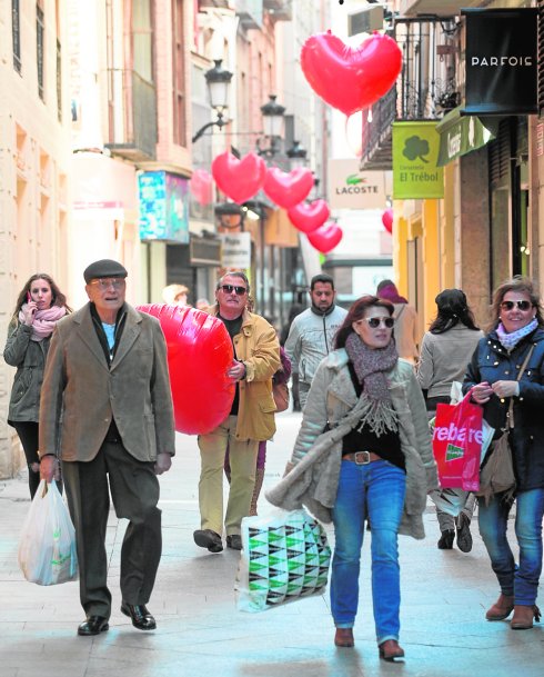 Divertidos globos rojos en forma de corazón adornan la calle Platería. Un viandante atrapa uno que se voló por el viento. 