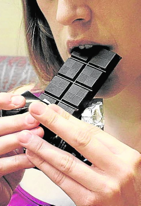 Una mujer degusta una tableta de chocolate.