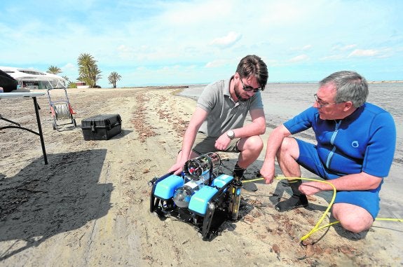 Manuel Erena, con traje azul, con uno de los drones que se utilizan para mapear las profundidades.