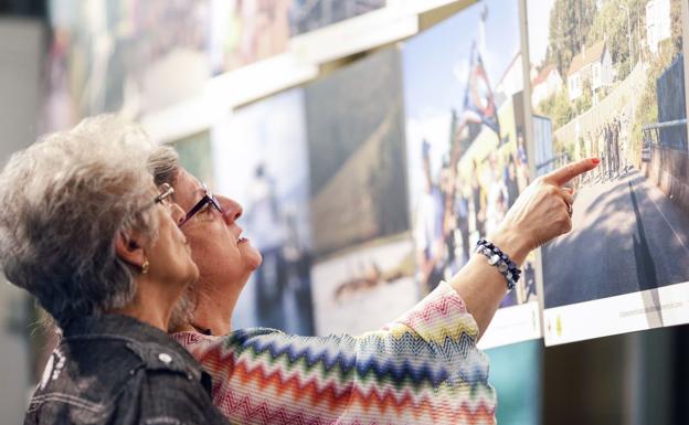 Dos visitantes a la exposición observan sus fotografías.