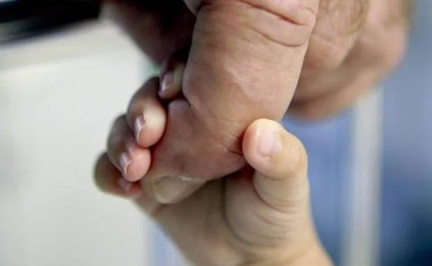 Imagen de archivo de la mano de un bebé y un adulto. 