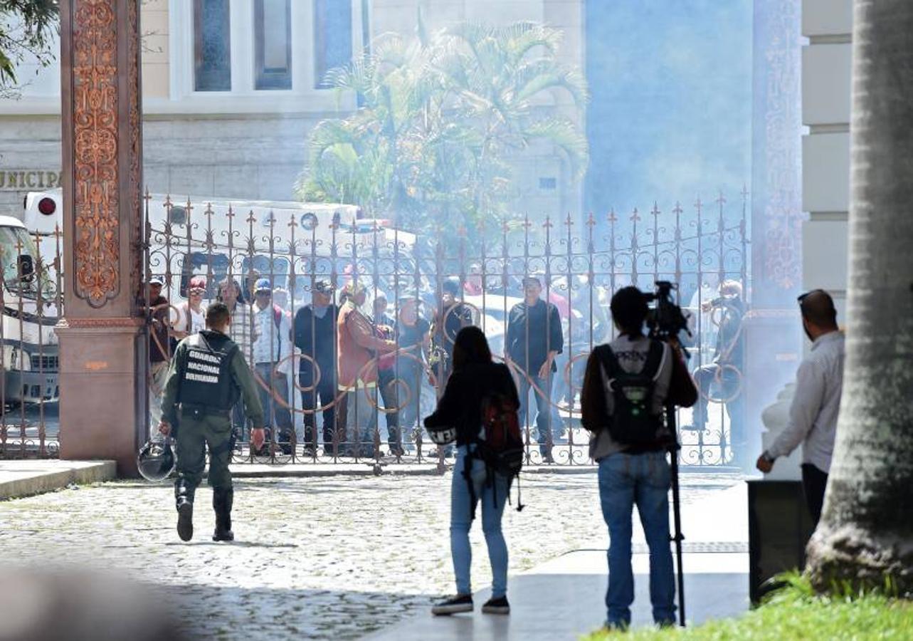 Decenas de personas, algunas encapuchadas, con palos y tubos, y vestidas de rojo, entraron a los jardines de la Asamblea Nacional y detonaron cohetes de fuegos artificiales, desatando el caos