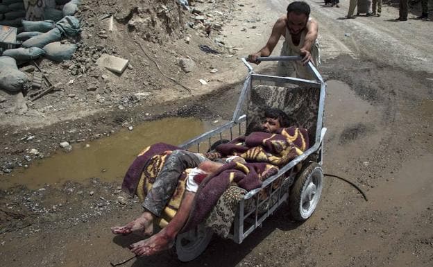Un civil evacúa a un herido en una camilla improvisada entre los escombros de la ciudad vieja de Mosul.