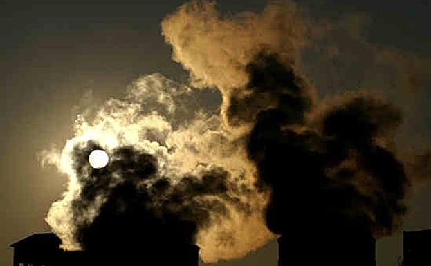 Chimeneas expelen sendas columnas de humo en una fábrica. 