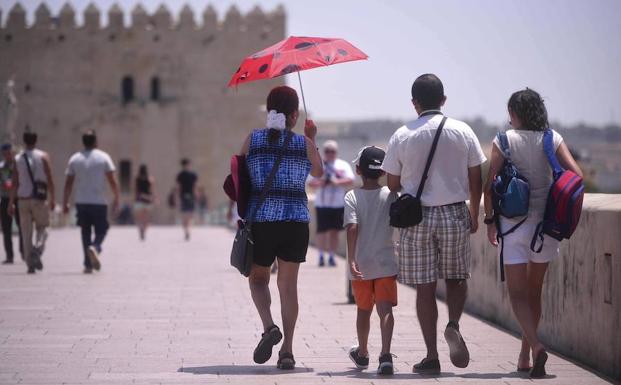 Paseantes se protegen del calor en Córdoba. 