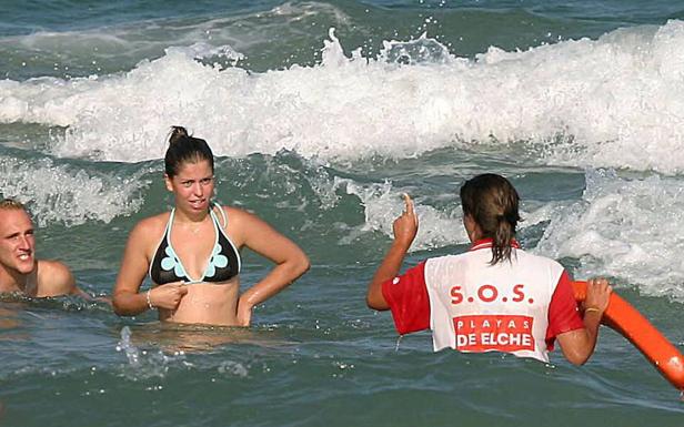 Una socorrista llama la atención a dos bañistas en la playa de El Rebolledo. 