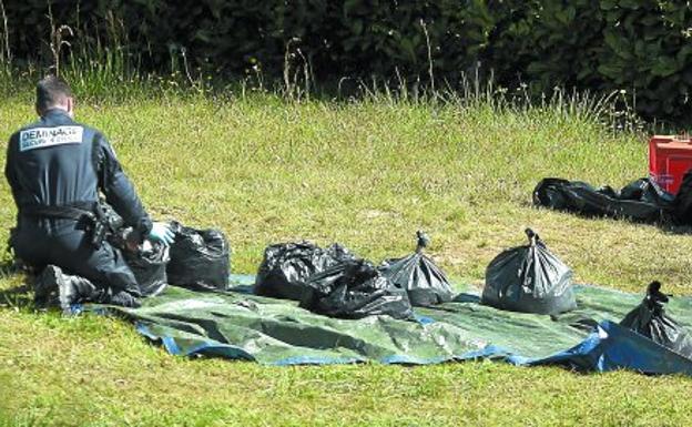 Un gendarme coloca sobre una lona bolsas con armas incautadas en un zulo de Saint-Pee-sur-Nivelle tras el desarme de ETA del 8 de abril.