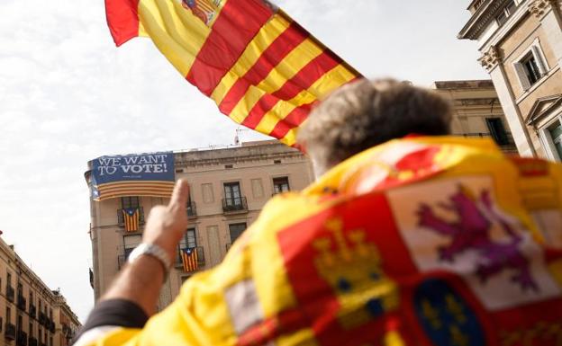 Un manifestante ataviado con una bandera española, ante un cartel a favor del referéndum.