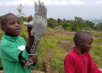Imagen secundaria 1 - Arriba, Guillermo coloca la prótesis completa de brazo en Kenia. Abajo, niños del orfanato aprenden el funcionamiento de las prótesis. A la derecha, la impresora Anet A8 con la que trabajó.