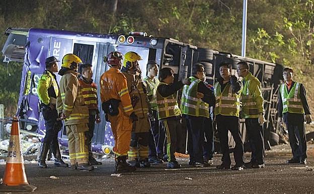 Varios oficiales hablan con los bomberos junto al vehículo. 