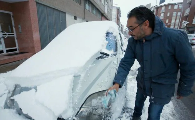 Un vecino de Ponferrada limpia su vehículo tras la nevada.