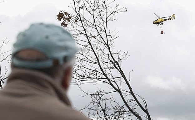 Un hombre contempla el trabajo de un helicóptero. 