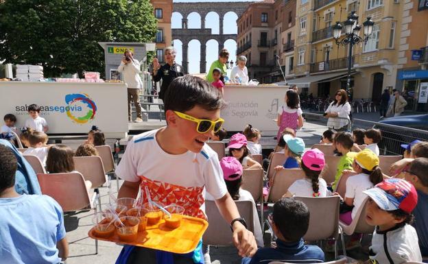 Un niño reparte vasos en Segovia. 