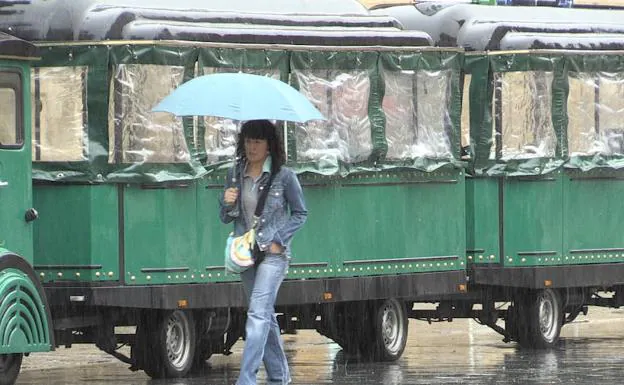 Una mujer se protege de la lluvia en León. 