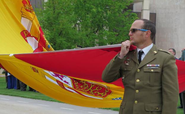 Un militar sostiene la bandera de España. 