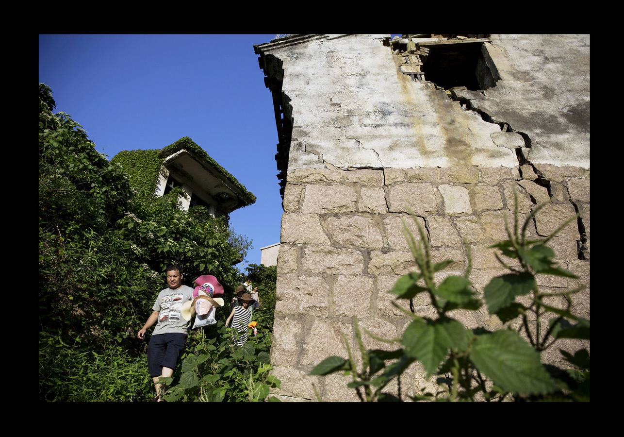 En Houtouwan, una pequeña aldea en las islas Shengsi, a 50 kilómetros de Shanghai, sólo vive un puñado de personas. Sus moradores, unos 2.000 pescadores y sus familias, tuvieron que emigrar a comienzos de la década de 1990 en busca de oportunidades, cuando la pequeña bahía se volvió insuficiente para atender la creciente demanda de la industria pesquera. El paso del tiempo y la naturaleza se han adueñado de las casas, que fueron la cuna de varias generaciones de pescadores, para abrazarlas y crear este sorprendente entorno: un fantasma verde, como un paisaje de otro mundo. 