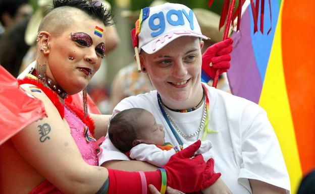 Una pareja de lesbianas posa con su bebé en el desfile del orgullo gay de Birmingham. 