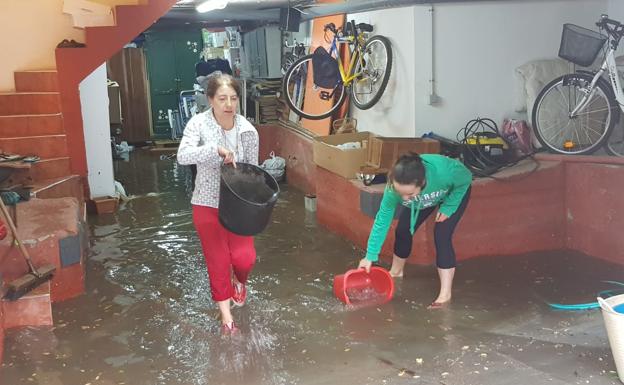 Dos vecinas de Puente Castro, achicando agua. 