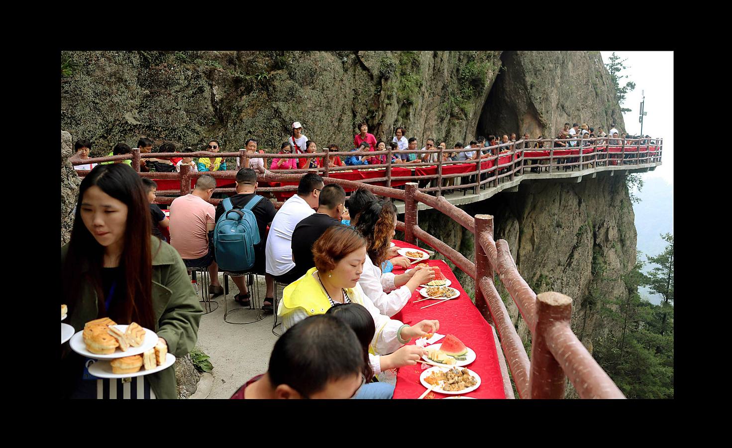 Centenares de turistas sin miedo a las alturas disfrutaron de cangrejos a la parrilla, champiñones fritos, frutas de temporada y vinos variados, suspendidos a más de 2.000 metros sobre el nivel del mar. El refrigerio de lujo, que formaba parte de un festival de verano celebrado en las paredes del Monte Laojun, en la provincia central de Henan, en China, se llevó a cabo en mesas dispuestas sobre una suerte de sendero de dos metros de ancho, unidas a la pared de roca. La montaña Laojun es uno de los destinos turísticos más populares de la provincia y es conocida porque fue el lugar de retiro de Laozi, el filósofo chino fundador del taoísmo. 