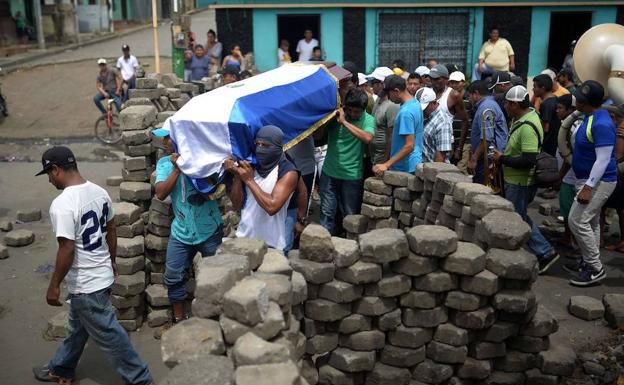 Varios nicaragüenses transportan el féretro de uno de sus compañeros falleciios. 