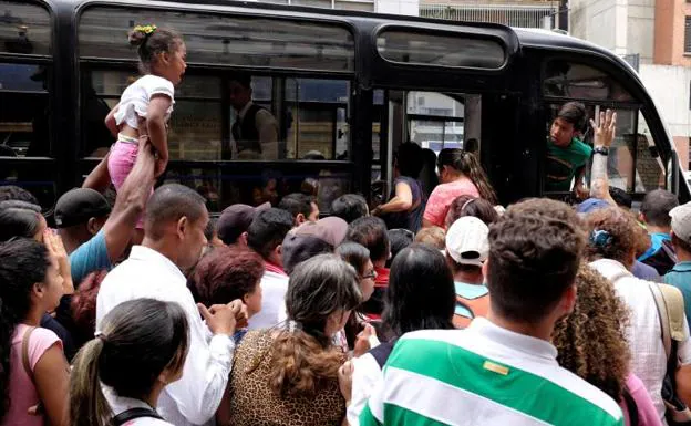 Ciudadanos intentan subir a un autobús en Caracas después de que un apagón dejara el metro sin servicio.