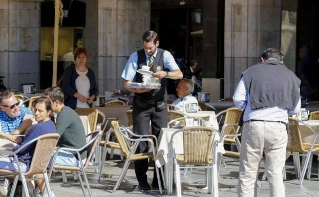 Un camarero, de los puestos con mayor creación de empleo, sirve una consumición en la Plaza Mayor de Salamanca. 