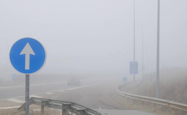 Un coche circula por el tramo de la A-6, cubierto de niebla. 