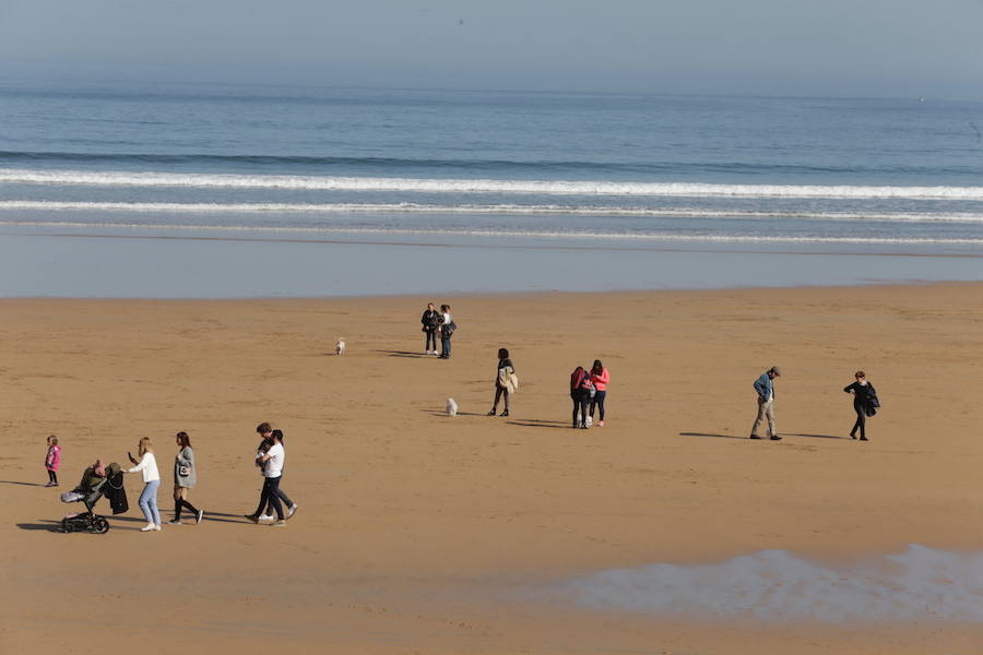 Decenas de personas se animaron a pasear por la Playa de San Lorenzo, bajo el sol y por la gran extensión de arena que dejó la bajamar