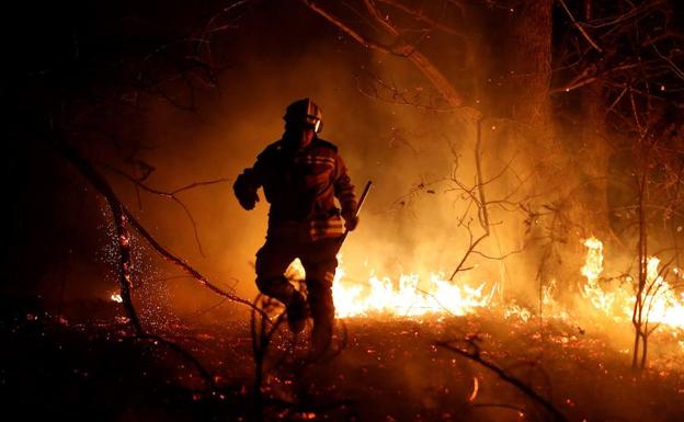 Los bomberos intentan sofocar el incendio que se ha producido este domingo en los alrededores de Labares (Asturias).