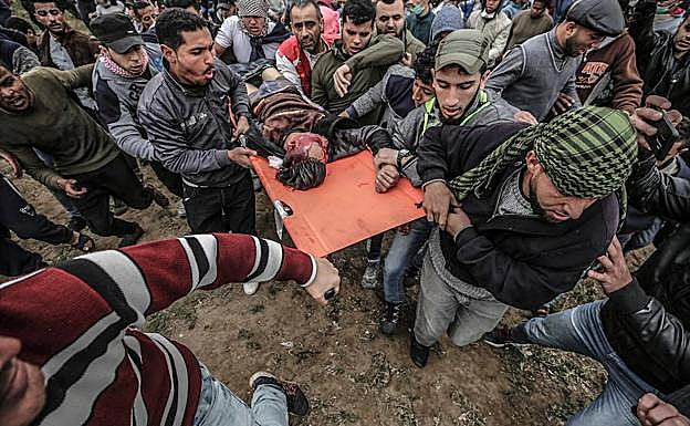 Manifestantes palestinos llevan el cuerpo de 17 años identificado como Adham Omara después de que un francotirador israelí lo disparara.