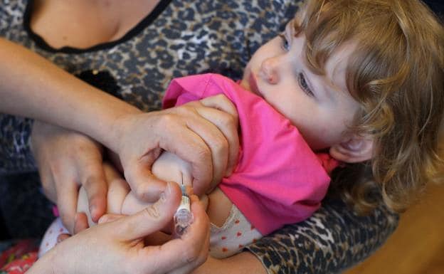 Una enfermera vacuna a una niña con la triple vírica. 