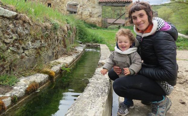 Zaida Largo, junto a su hijo Mauro en el pilón que tienen al lado de su casa en Celada de Roblecedo. 