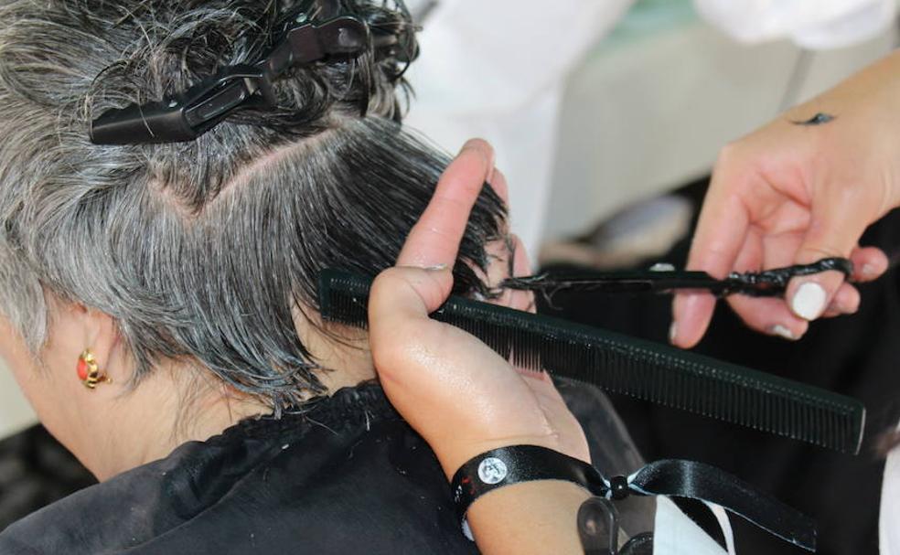 Una peluquera corta el cabello de una mujer. 